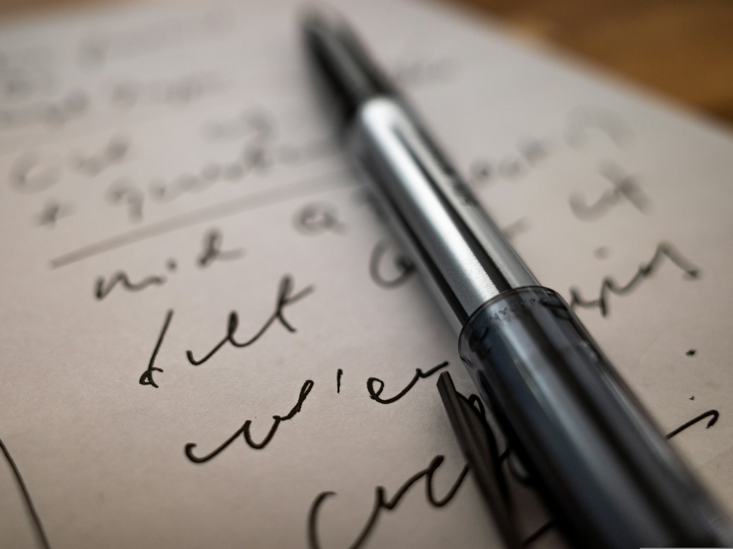 A pen rests on a sheet of handwritten notes.