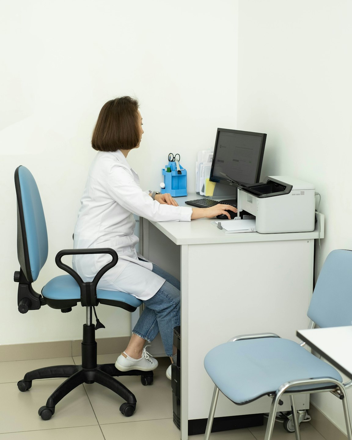 Medical professional typing on a computer at a minimalist office desk.
